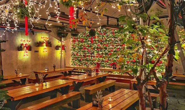 A restaurant patio decorated for the holidays with string lights, garland, and festive greenery